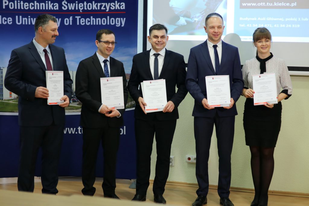 Pięć osób w garniturach i sukience trzyma dokumenty. Kontekst: Politechnika Świętokrzyska, wręczenie grantów.