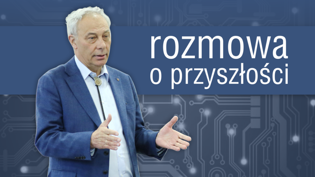 Mężczyzna w garniturze mówi, gestykulując. Na tle widnieje napis 