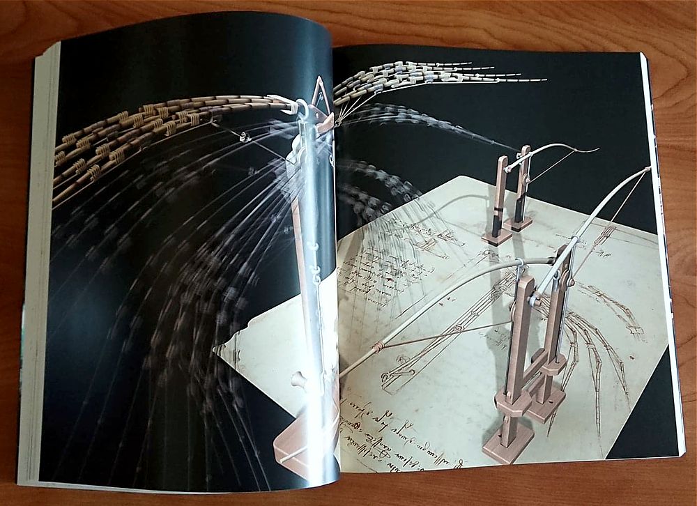 Model mechanicznych skrzydeł i łuków na tle szkiców. Kluczowe obiekty: modele skrzydeł, łuki, szkice.