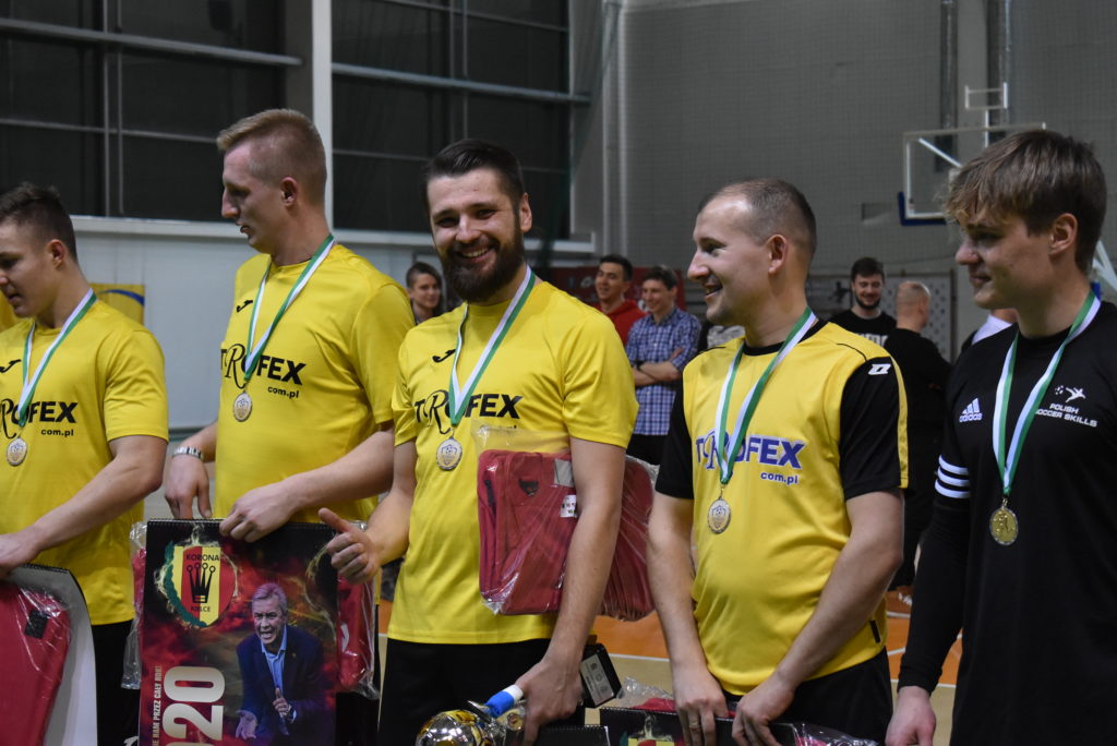 Mężczyźni w żółtych koszulkach z medalami i plakatami. Kontekst: ceremonia wręczenia nagród.