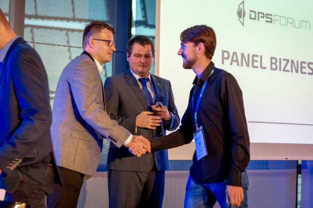 Dwóch mężczyzn w garniturach ściska sobie dłonie. Na ekranie widnieje napis "PANEL BIZNES".