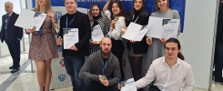 Grupa osób pozuje z dyplomami i medalami na tle banera "International Warsaw Invention Show".