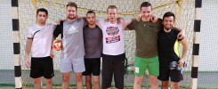 Sześciu mężczyzn stoi przed bramką do piłki ręcznej. Mają na sobie sportowe stroje.