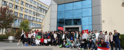 Grupa studentów pozuje do zdjęcia przed budynkiem uczelni. Widać flagi Turcji, Egiptu i Algierii.
