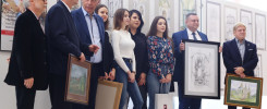 Ludzie pozują z obrazami na wystawie prac studenckich. Wystawa prac studenckich.