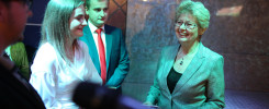 Kobieta w marynarce i mężczyzna w garniturze rozmawiają. W tle widać mikrofon.