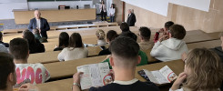 Wykład o wymianie akademickiej Erasmus+. W sali wykładowej siedzą studenci, a na scenie stoi prelegent.