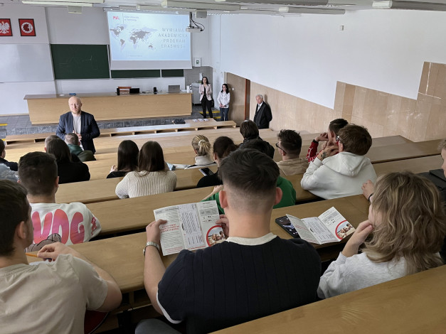 Wykład o wymianie akademickiej Erasmus+. W sali wykładowej siedzą studenci, a na scenie stoi prelegent.