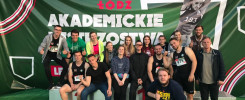 Grupa młodych ludzi pozuje do zdjęcia na tle baneru "Akademickie Mistrzostwa Łodzi".