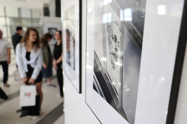 Wystawa sztuki z ludźmi oglądającymi obrazy. Kluczowe obiekty: obrazy, ludzie, galeria. Kontekst: wydarzenie kulturalne.
