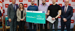 Grupa osób prezentuje czek na 6000 zł z okazji I miejsca na hackathonie.