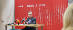Mężczyzna w okularach siedzi przy stole z mikrofonami. Kontekst: konferencja prasowa Politechniki Świętokrzyskiej.