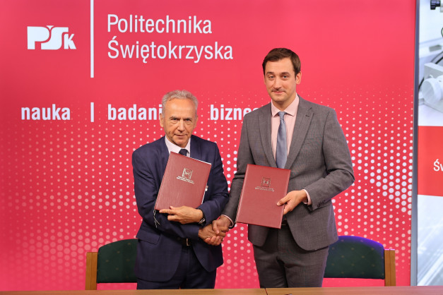 Dwóch mężczyzn w garniturach trzyma dokumenty. Tło to czerwona ściana z napisem "Politechnika Świętokrzyska".