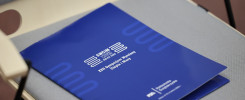 Niebieska okładka sympozjum "SWCIM KIEŁCE 2025" leży na krześle. Kluczowe obiekty: okładka, krzesło.