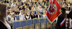 Dzieci i dorośli siedzą na widowni. Widać flagę z napisem "POLITECHNIKA ŚWIĘTOKRZYSKA KIELCE".