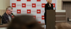 Kobieta przemawia przy mównicy na tle baneru Politechniki Świętokrzyskiej. W tle mężczyzna.