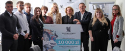 Grupa osób stoi przed banerem z logo Trust Investment i informacją o nagrodzie 10 000 zł.