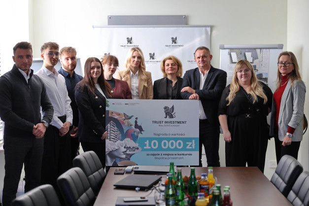 Grupa osób stoi przed banerem z logo Trust Investment i informacją o nagrodzie 10 000 zł.