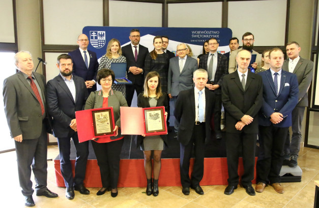 Grupa osób pozuje do zdjęcia z dyplomami. W tle widnieje logo województwa świętokrzyskiego.