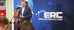 Mężczyzna w garniturze przemawia przy mikrofonie. Tło to baner "ERC SPACE AND ROBOTICS EVENT".