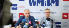 Dwóch mężczyzn siedzi przy stole z mikrofonami. W tle logo Politechniki Świętokrzyskiej.