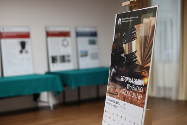 Plakat z młotkiem sędziowskim i książkami. Kontekst: seminarium prawnicze.