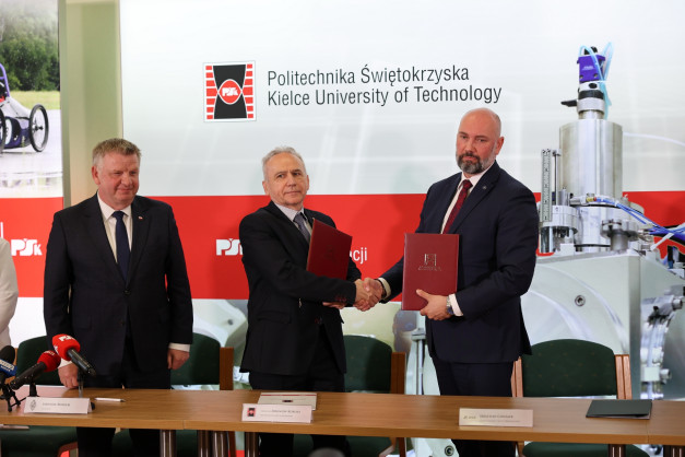 Trzech mężczyzn w garniturach ściska sobie dłonie, trzymając dokumenty. W tle logo Politechniki Świętokrzyskiej.