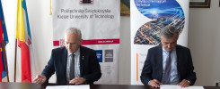 Dwóch mężczyzn w garniturach podpisuje dokumenty przy stole. W tle banery Politechniki Świętokrzyskiej i DS Smith.
