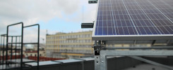 Panel fotowoltaiczny na dachu, widok na budynek i drabinkę. Kontekst: miejski, instalacja OZE.
