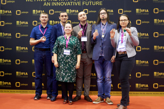 Osoby z medalami na tle logotypów IFIA i Palexpo. Kontekst: wydarzenie związane z innowacjami.