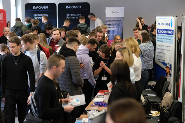 Ludzie na targach budowlanych. Stoiska firm, materiały informacyjne, rozmowy.