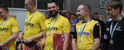 Mężczyźni w żółtych koszulkach z medalami i plakatami. Kontekst: ceremonia wręczenia nagród.