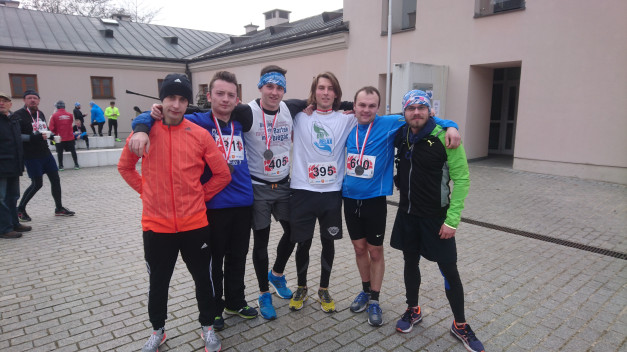 Sześciu mężczyzn w strojach sportowych i z medalami pozuje do zdjęcia. Kontekst: bieg.
