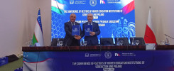 Dwóch mężczyzn podpisuje dokumenty na konferencji rektorów uczelni Uzbekistanu i Polski.
