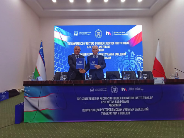 Dwóch mężczyzn podpisuje dokumenty na konferencji rektorów uczelni Uzbekistanu i Polski.