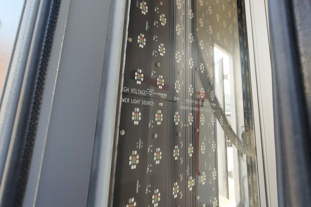 Panel z wieloma diodami LED i ostrzeżeniami o wysokim napięciu. Kontekst: zewnętrzna instalacja oświetleniowa.