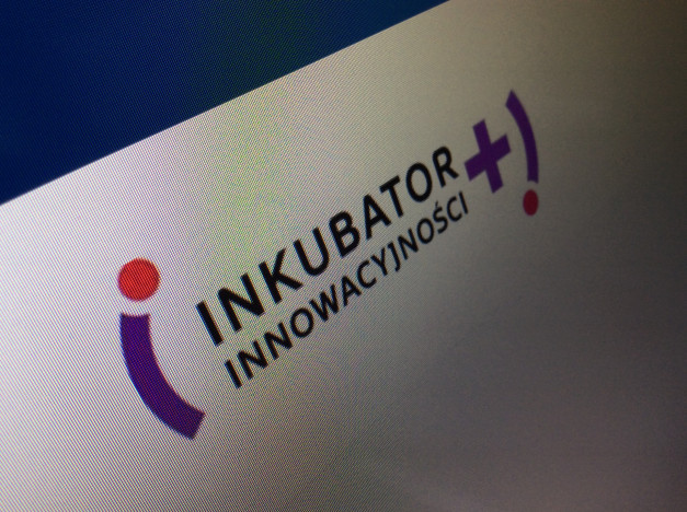 Logo "INKUBATOR INNOWACYJNOŚCI" z fioletowym znakiem plus i czerwoną kropką.