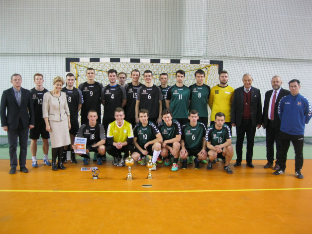 Drużyna sportowa pozuje do zdjęcia z pucharami i dyplomem.