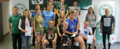 Grupa osób pozuje do zdjęcia z dyplomami i medalami. W tle baner "Akademicki Związek Sportowy".