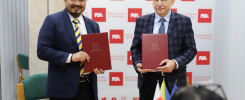 Dwóch mężczyzn w garniturach trzyma czerwone teczki. W tle logo Politechniki Świętokrzyskiej.