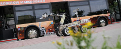 Autobus z napisem "ROBOTÓW MARSJAŃSKICH" i łazik marsjański. Kluczowe obiekty: autobus, łazik marsjański, robotyczne ramię.