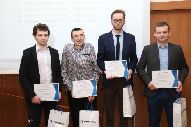Czterech mężczyzn odbiera dyplomy i torby z logo Transition. Kontekst: uroczystość wręczenia nagród.
