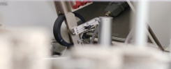 Mechanizm z czarnym kołem, metalowymi elementami i szarym złączem. Kontekst: przemysłowy, produkcyjny.