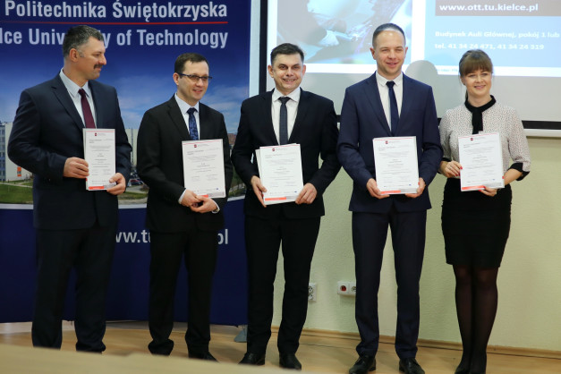 Pięć osób w garniturach i sukience trzyma dokumenty. Kontekst: Politechnika Świętokrzyska, wręczenie grantów.