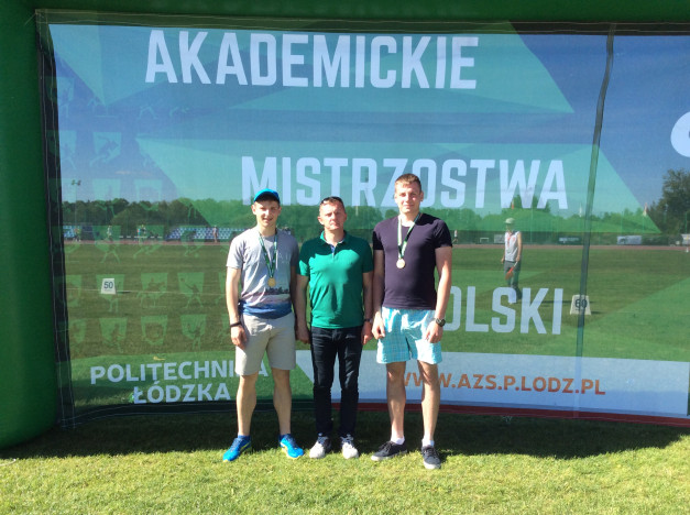Trzech mężczyzn stoi przed banerem "Akademickie Mistrzostwa Polski Politechnika Łódzka".