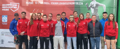 Grupa młodych ludzi w strojach sportowych pozuje przed banerem "LEKKA ATLETYKA POZNAŃ 19-21.05.2023".