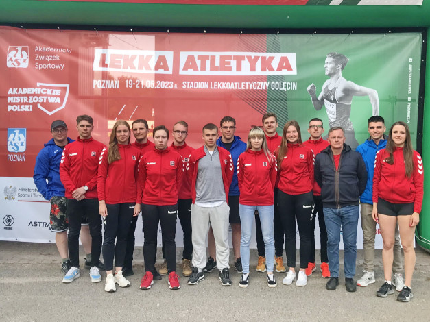 Grupa młodych ludzi w strojach sportowych pozuje przed banerem "LEKKA ATLETYKA POZNAŃ 19-21.05.2023".