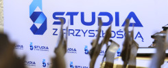 Napis "STUDIA Z PRZYSZŁOŚCIĄ" na białym tle. W tle widać metalowe elementy.