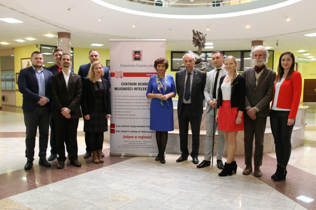 Grupa osób stoi przed banerem Centrum Ochrony Własności Intelektualnej Politechniki Świętokrzyskiej.