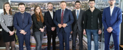 Grupa osób pozuje przed banerem z logo Kielc. W tle widoczne miasto.
